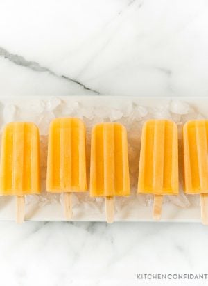Cantaloupe popsicles in a row on an ice-covered platter.