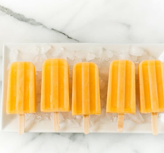 Cantaloupe popsicles in a row on an ice-covered platter.