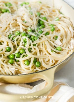 Spaghetti tossed with sauce and fresh peas in a large dish.