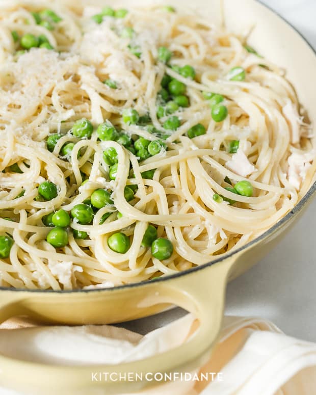 Spaghetti tossed with sauce and fresh peas in a large dish.