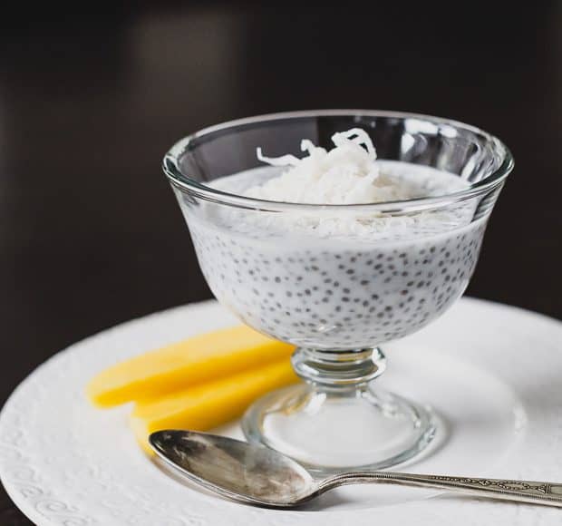 A serving glass on a white plate filled with Coconut Chia Pudding.