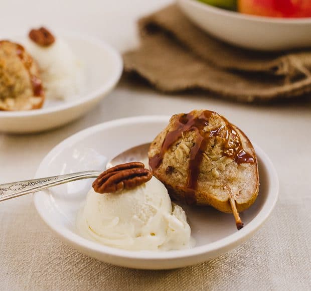 An individual Stuffed Pear Crisp in a bowl served with ice cream and a drizzle of caramel.