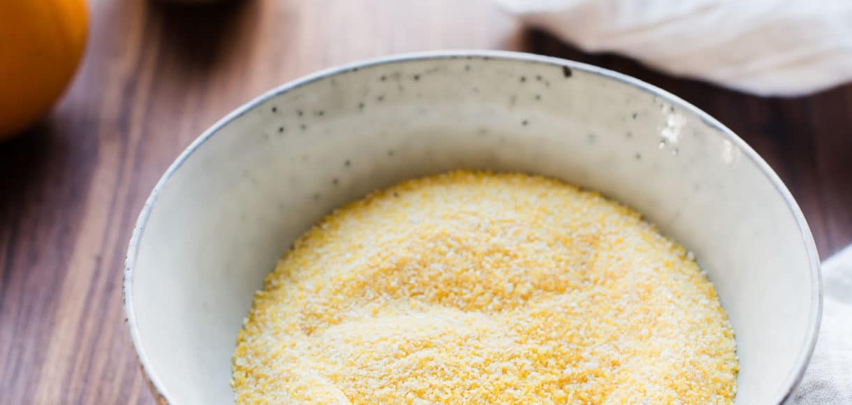 Polenta in a pottery bowl on a wooden counter top.