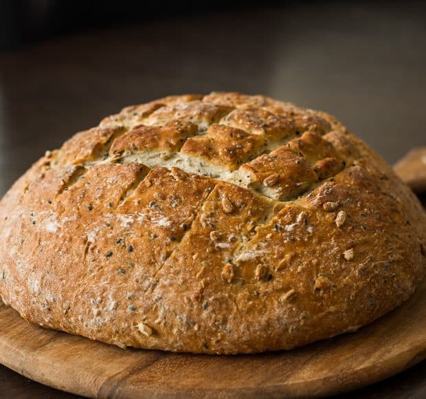 A loaf of homemade Seed Bread on a wooden board.