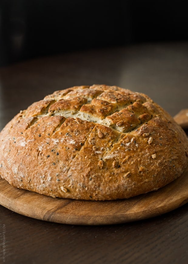 A loaf of homemade Seed Bread on a wooden board.