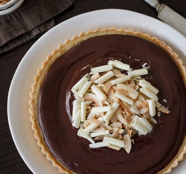 Coconut Custard Tart with Chocolate Ganache on a white serving plate.