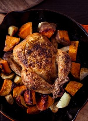 Roasted Cornish Hens and chopped sweet potatoes in a cast iron skillet.