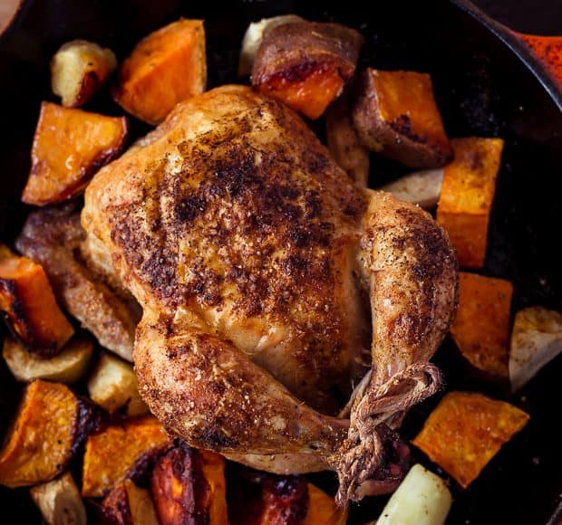 Roasted Cornish Hens and chopped sweet potatoes in a cast iron skillet.