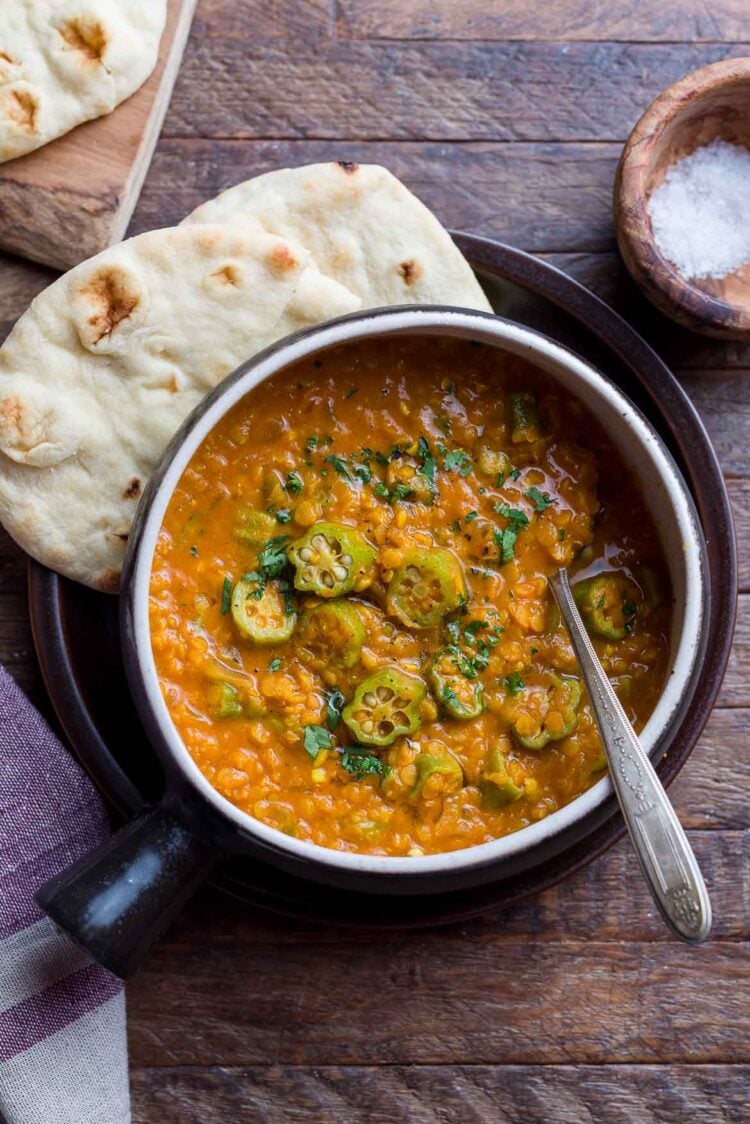 Lentil Okra Curry in a bowl, with warm naan.