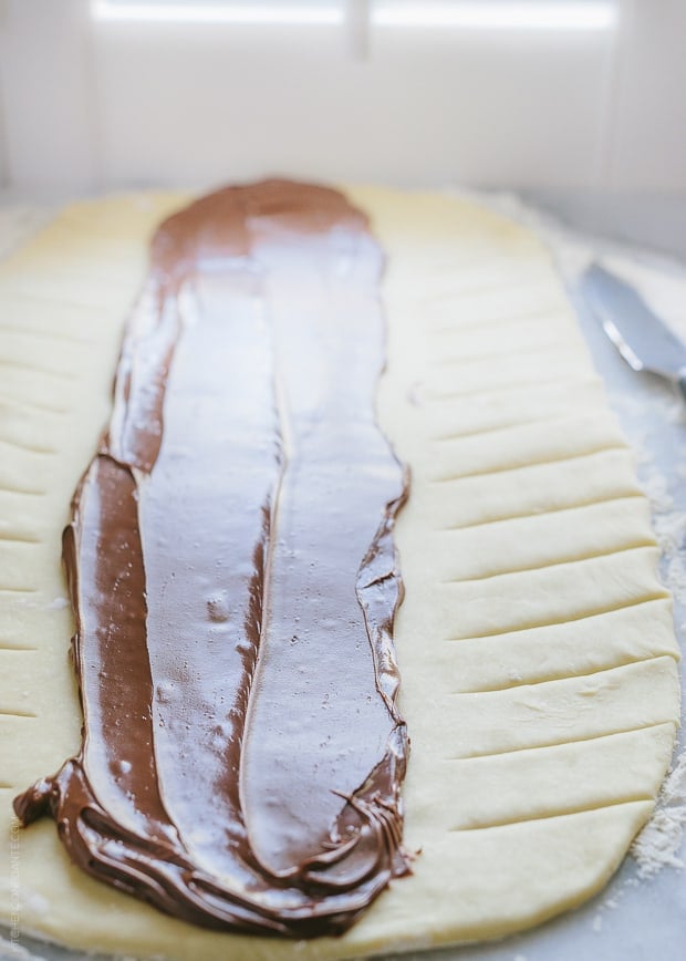 Spreading Nutella onto yeast dough rolled thin.