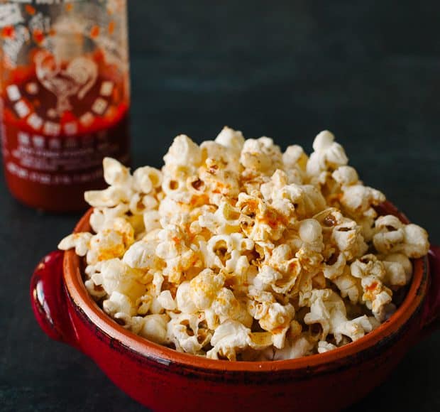 A red bowl filled with spicy sriracha popcorn.