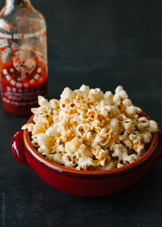 A red bowl filled with spicy sriracha popcorn.
