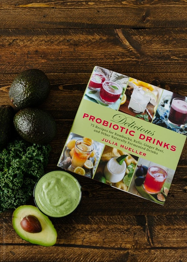 Delicious Probiotic Drinks cookbook on a wooden background with Avocado Kale Superfood Smoothie, avocados, and kale