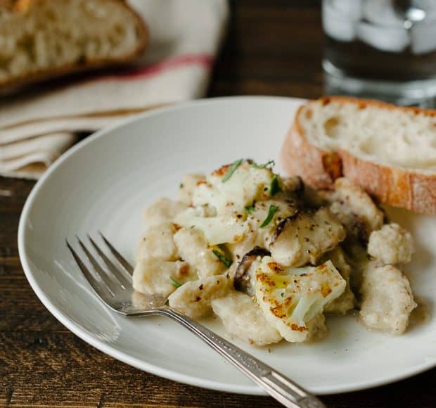 A white plate of Cauliflower Gnocchi with Creamy Cauliflower-Shiitake Mushroom Sauce.