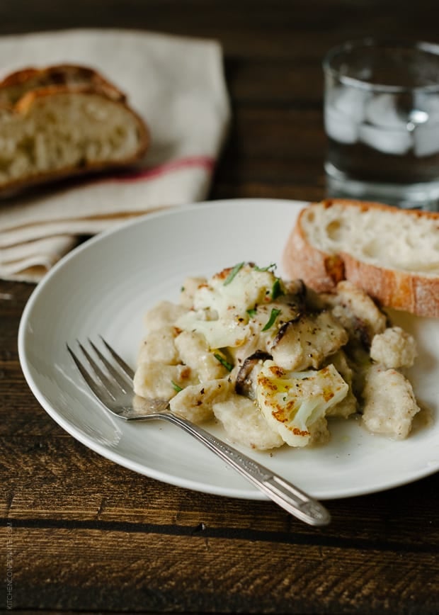 A white plate of Cauliflower Gnocchi with Creamy Cauliflower-Shiitake Mushroom Sauce.