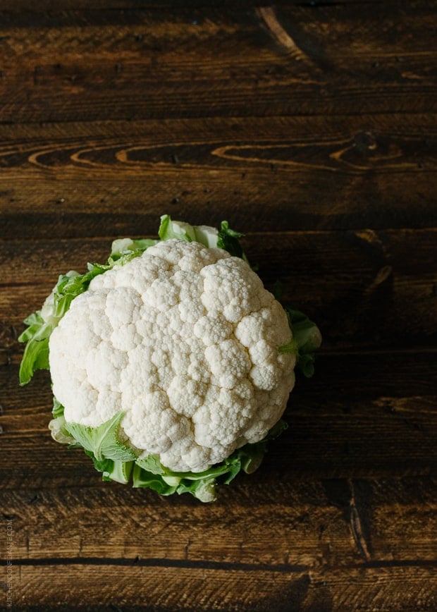 A head of cauliflower on a wooden surface.