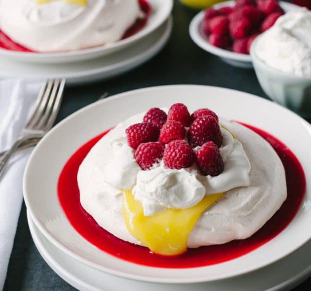 Meyer Lemon and Raspberry Pavlova swimming in a pool of homemade raspberry sauce and topped with fresh whipped cream and Meyer Lemon curd.