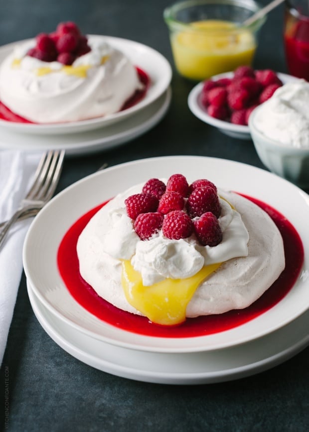 Meyer Lemon and Raspberry Pavlova swimming in a pool of homemade raspberry sauce and topped with fresh whipped cream and Meyer Lemon curd.