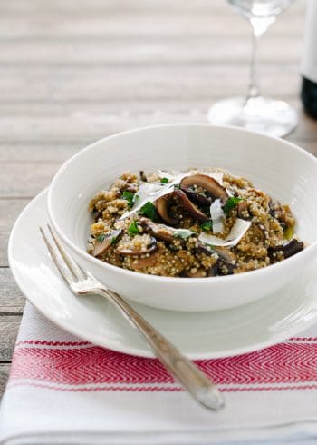 A white bowl on a table filled with Mushroom Quinoa Risotto.