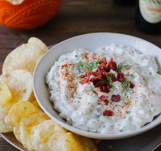 A bowl of Bacon Leek Dip served alongside potato chips.