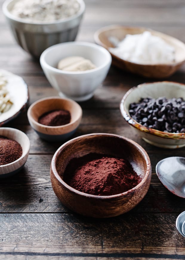 Cocoa powder and espresso powder in wooden bowls on a wooden surface.