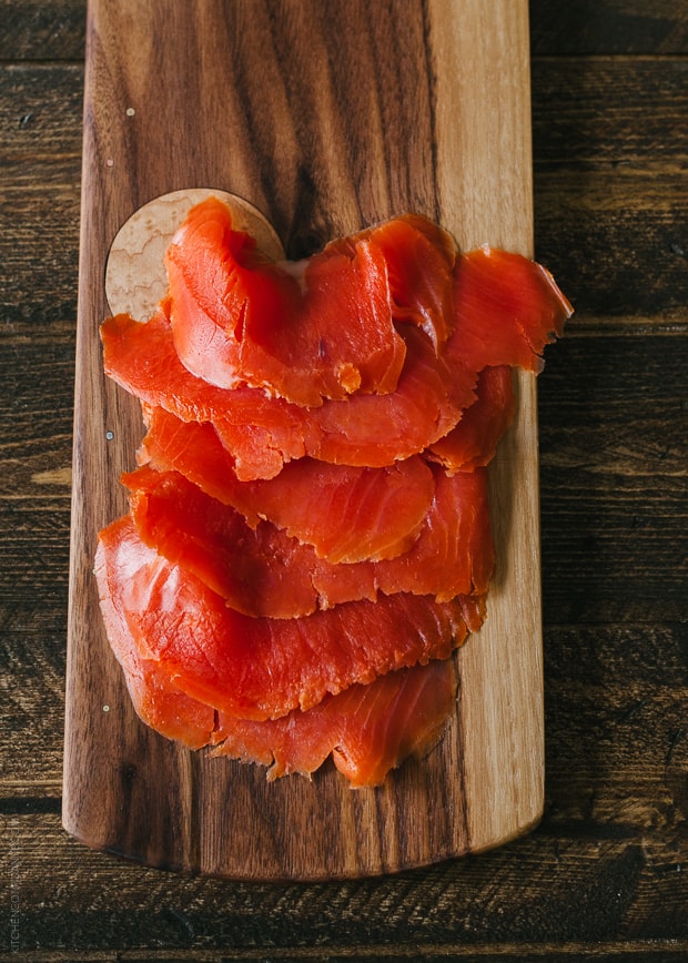 Slices of smoked salmon on a wooden serving board.