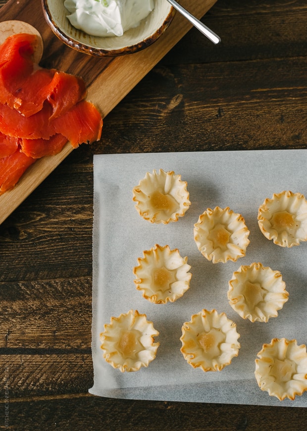 Phyllo cups on a piece of parchment surrounded by smoked salmon and goat cheese.