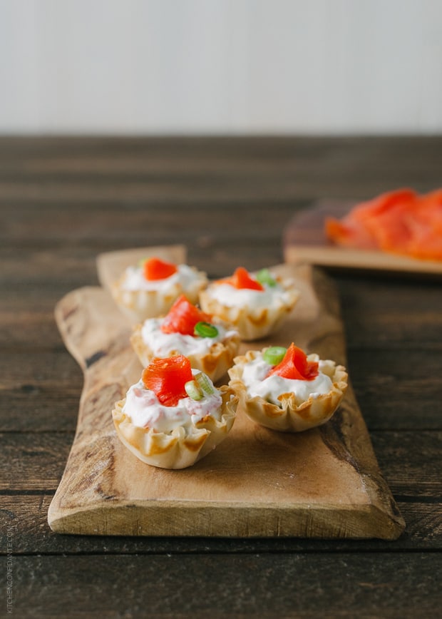 Smoked Salmon Phyllo Bites with Wasabi Goat Cheese on a wooden serving board.