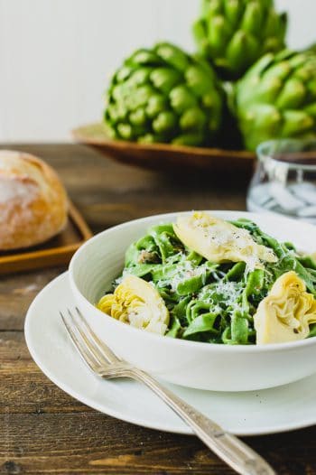 A bowl of fresh homemade spinach fettuccine with creamy artichokes.
