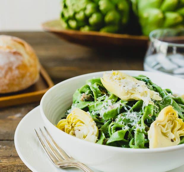 A bowl of fresh homemade spinach fettuccine with creamy artichokes.