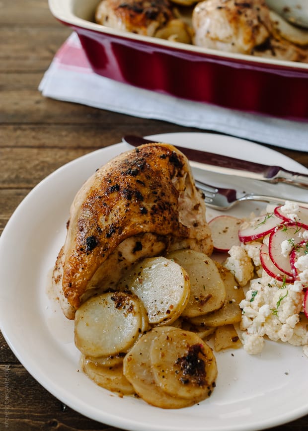 Roast Chicken served alongside roasted potatoes and a salad of sliced radishes.