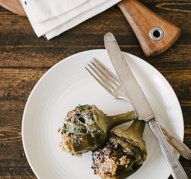 Two Toasted Quinoa Stuffed Artichokes arranged on a white plate.