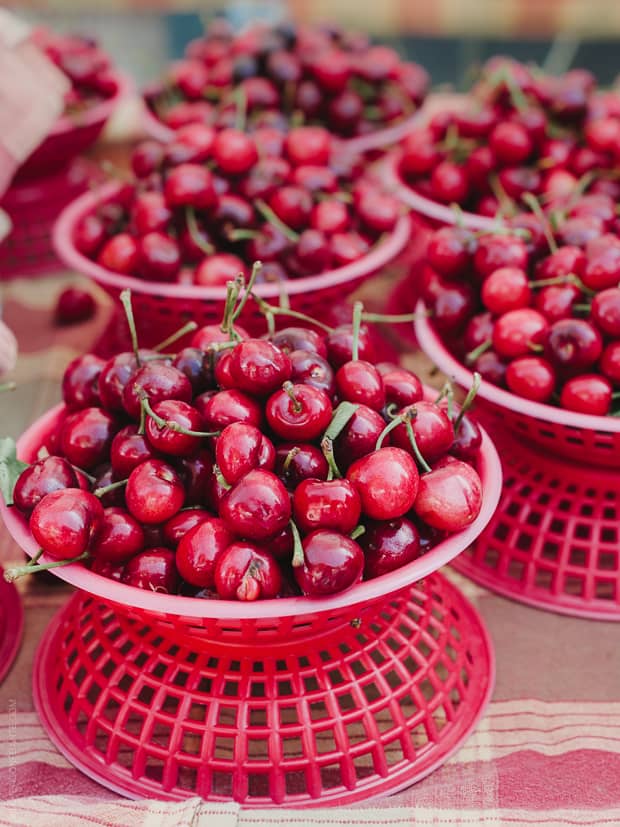 Fresh cherries in red baskets at a farmer's market.