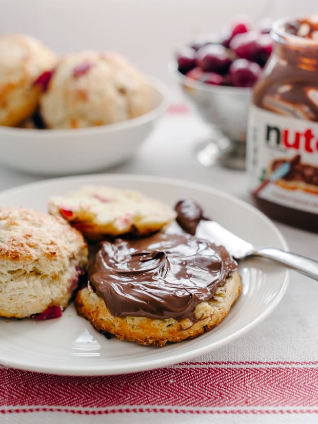 Spreading Nutella onto a fresh cherry scone.