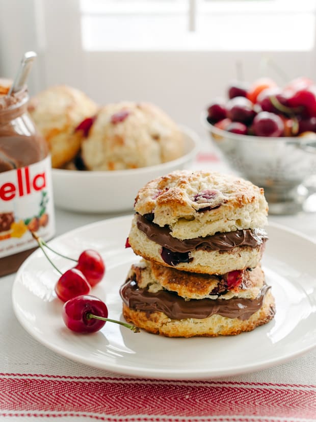 Cherry Nutella Scones split open, spread with Nutella, and stacked on a white plate.