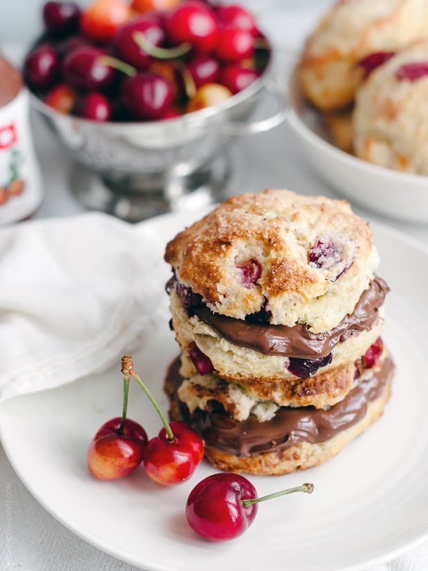 Cherry Nutella Scones stacked on a white plate with fresh cherries.