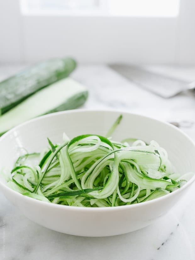 A white bowl filled with julienned cucumbers.