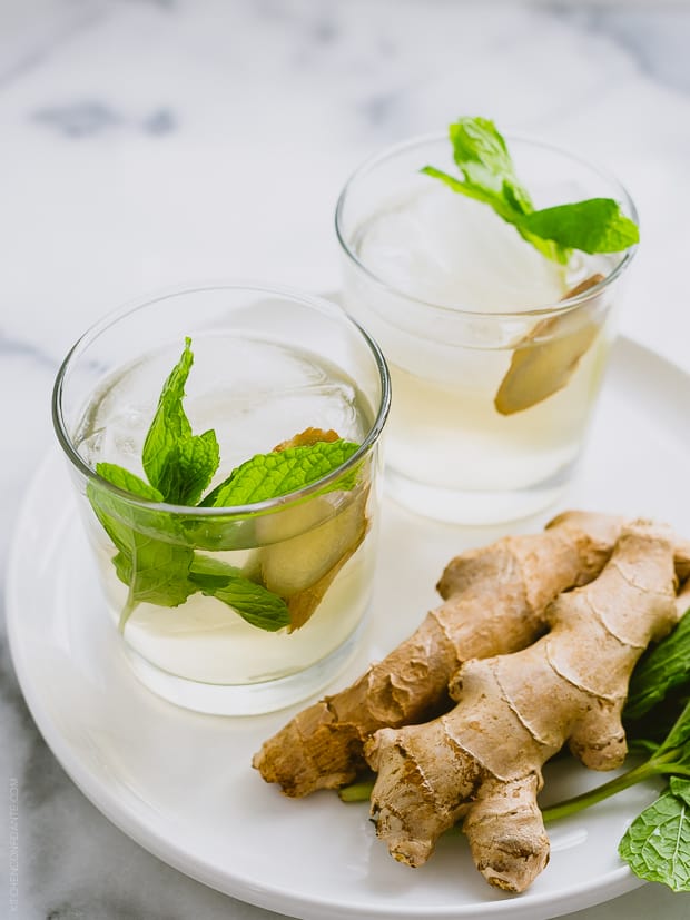 Glasses filled with coconut water coolers alongside fresh ginger.