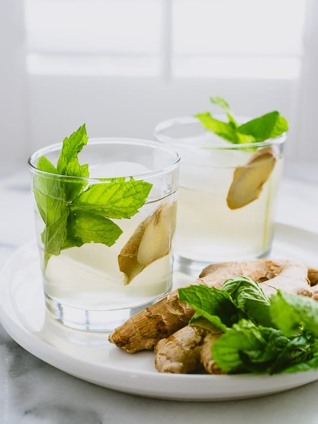 Two coconut water coolers garnished with mint and ginger.