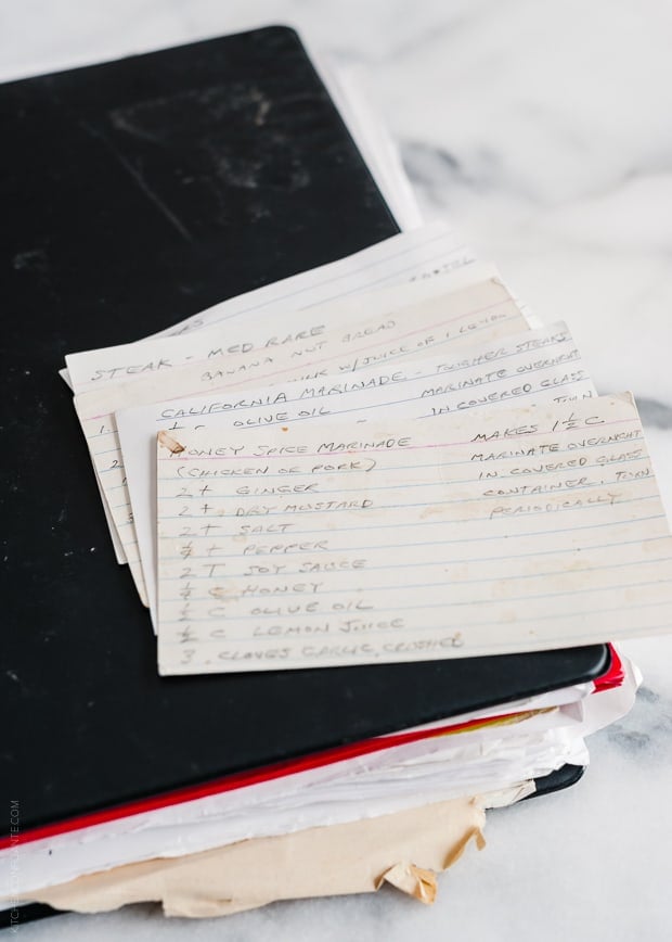 Handwritten recipe cards on top of a larger binder of recipes.