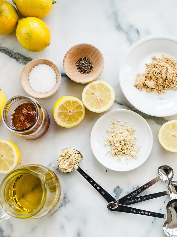 Honey, spices, and lemons arranged on a marble surface.