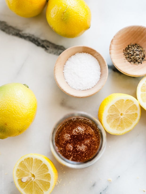 Spices and halved lemons on a marble surface.