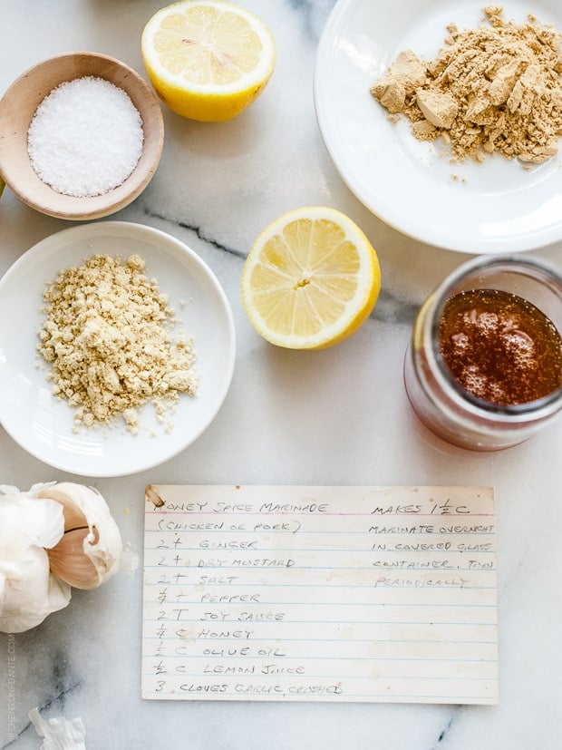 A handwritten recipe card for Honey Spice Marinated Grilled Chicken surrounded by ingredients.