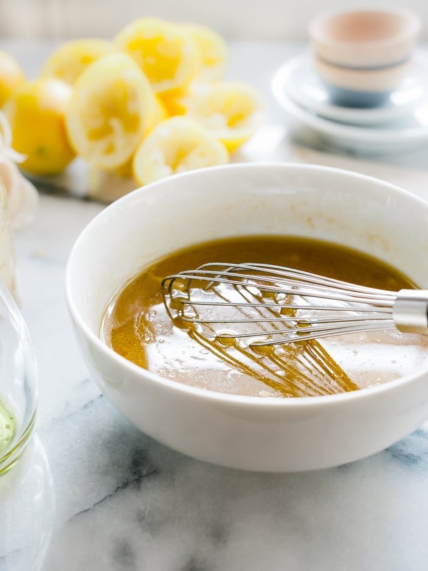 Whisking the marinade for Honey Spice Marinated Grilled Chicken in a white bowl.