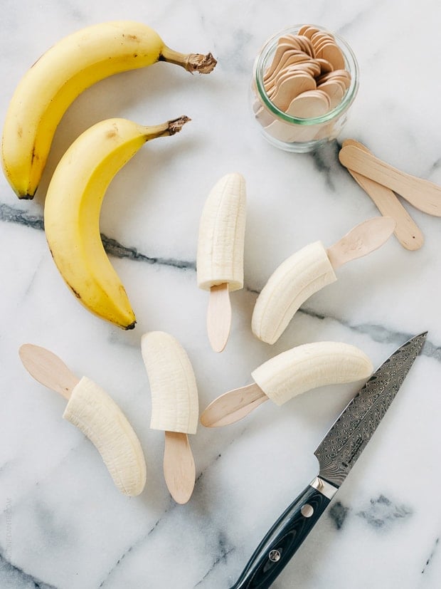 Inserting popsicle sticks into halved bananas.