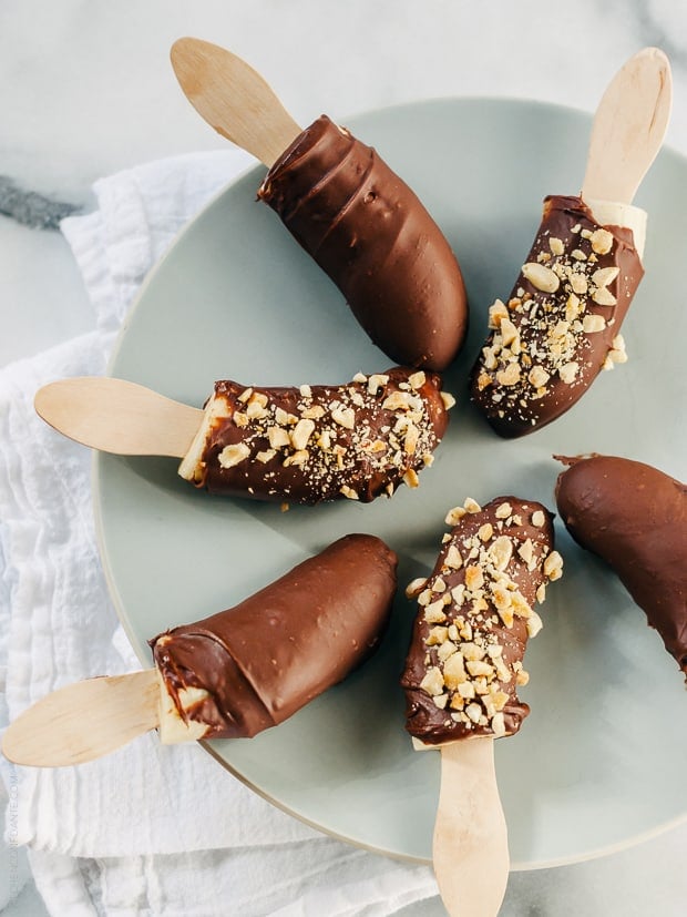 Six Nutella-Dipped Frozen Bananas arranged on a plate.