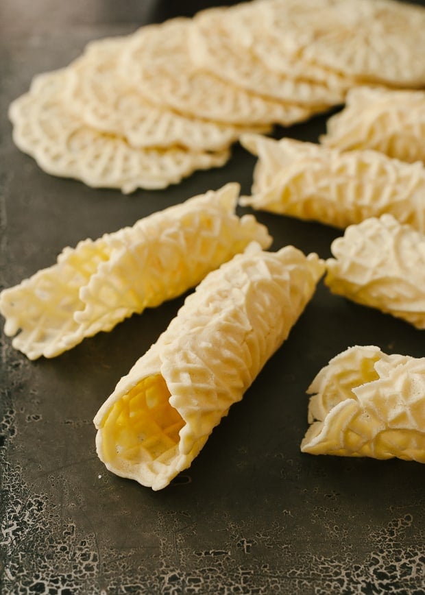 Rolled Pizzelle cookies on a dark background.