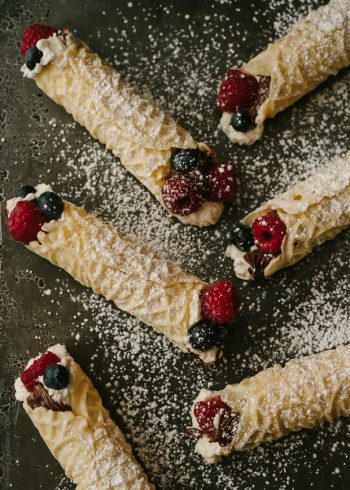 Rolled pizzelle cookies filled with whipped cream, berries, and Nutella.