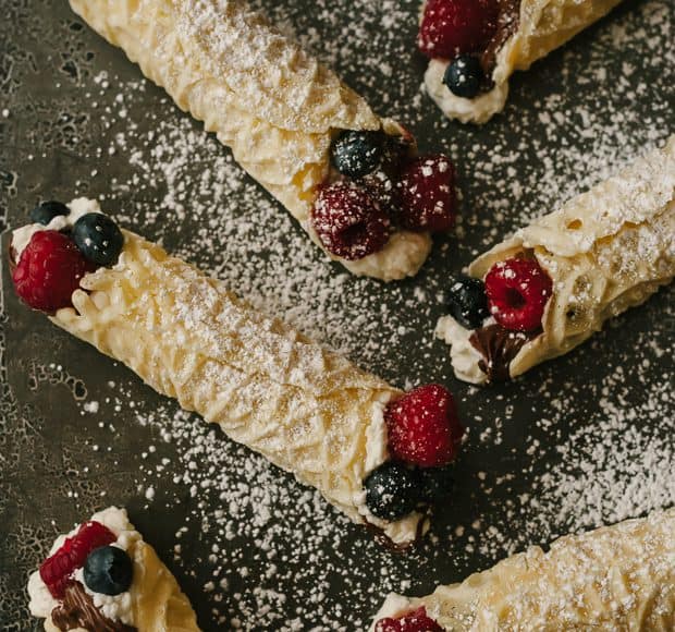 Rolled pizzelle cookies filled with whipped cream, berries, and Nutella.