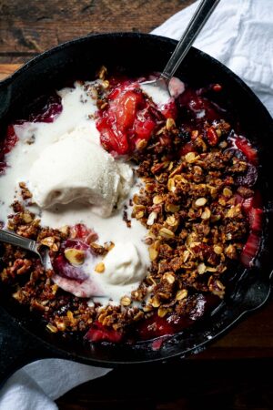 Stovetop Rhubarb-Cherry Crisp in a skillet topped with ice cream.